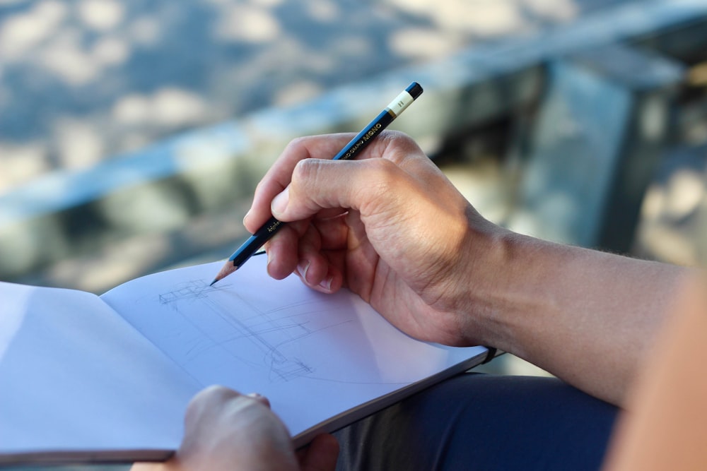 person sketching on white pad