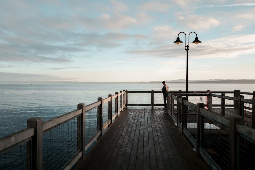 man standing on brown dock near lights during daytime