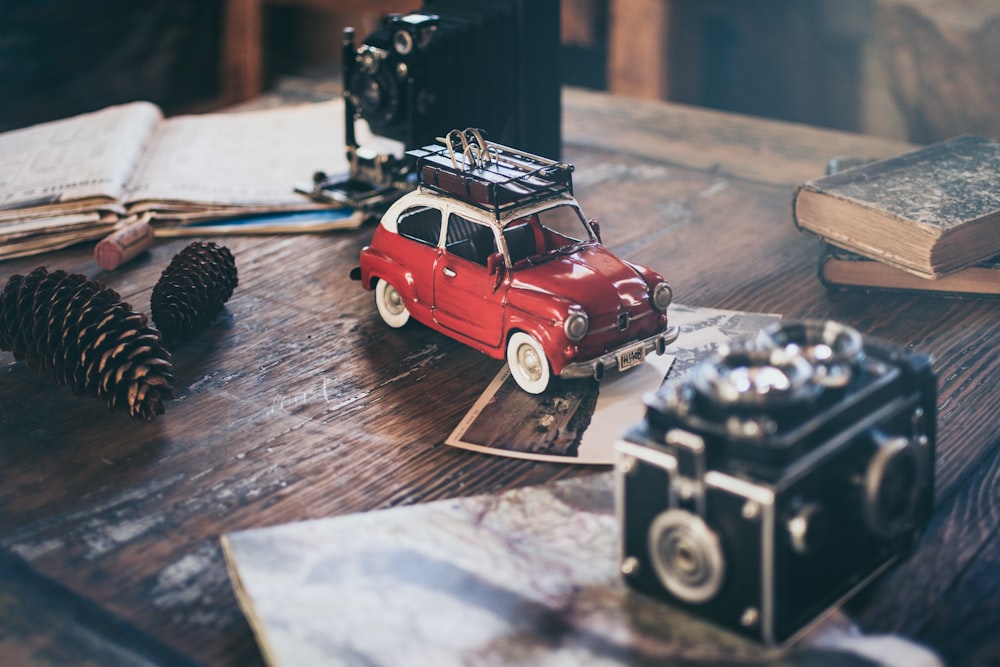 Fokusfotografie eines roten Fahrzeug-Druckgussmodells neben Tannenzapfen