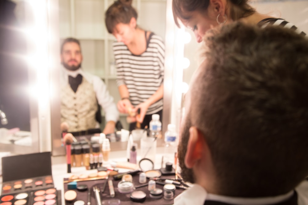 a group of people standing around a table with makeup