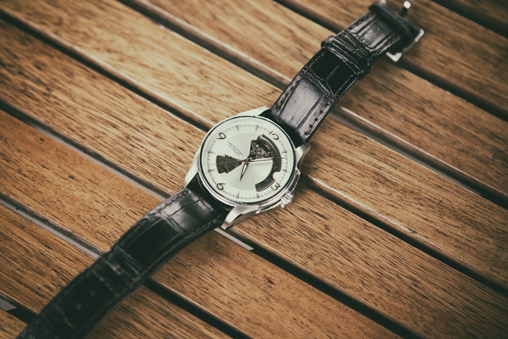 round silver-colored analog watch with black leather strap