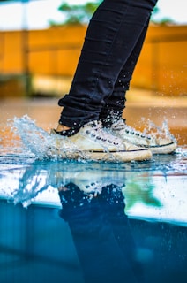SaltDan shoes stepping through a shallow stream with splashing water droplets.