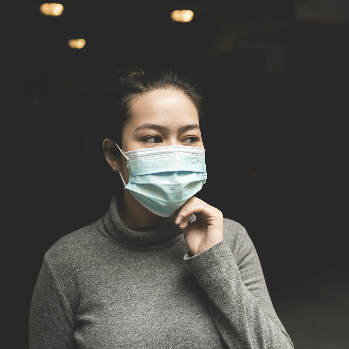 woman wearing teal mask and gray turtle-neck shirt