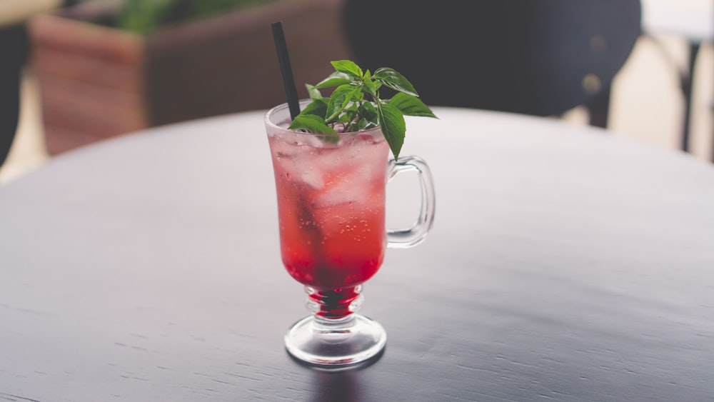 clear mug with straw and leafed plant