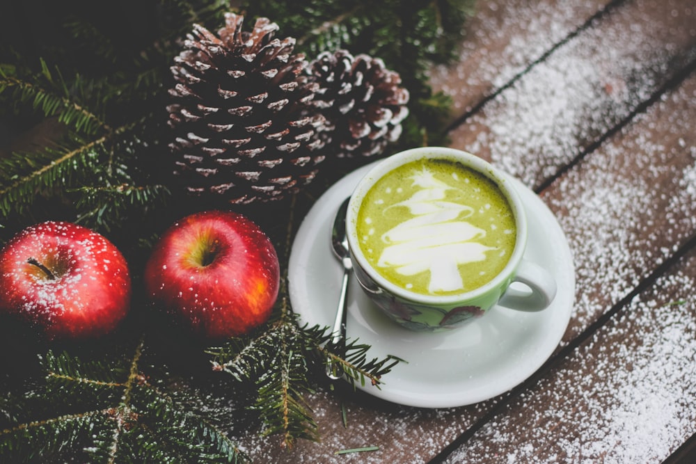 white ceramic mug beside red apples