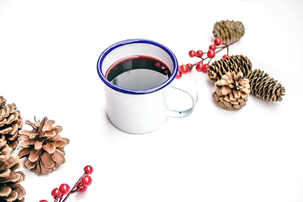 black liquid on white mug beside pine cones