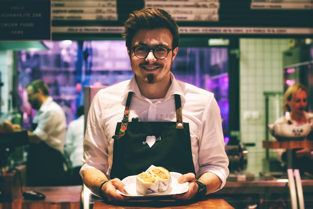 uomo che tiene piatto di pesce sul piatto