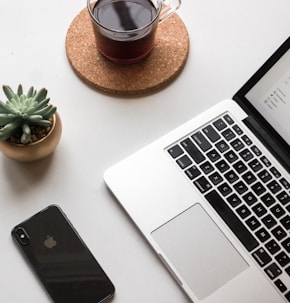 space gray iPhone X beside turned on laptop beside coffee and succulent plant