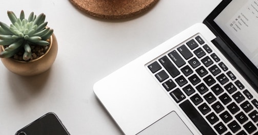 space gray iPhone X beside turned on laptop beside coffee and succulent plant