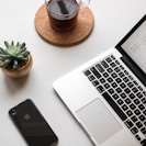 space gray iPhone X beside turned on laptop beside coffee and succulent plant