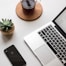 space gray iPhone X beside turned on laptop beside coffee and succulent plant