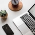 space gray iPhone X beside turned on laptop beside coffee and succulent plant