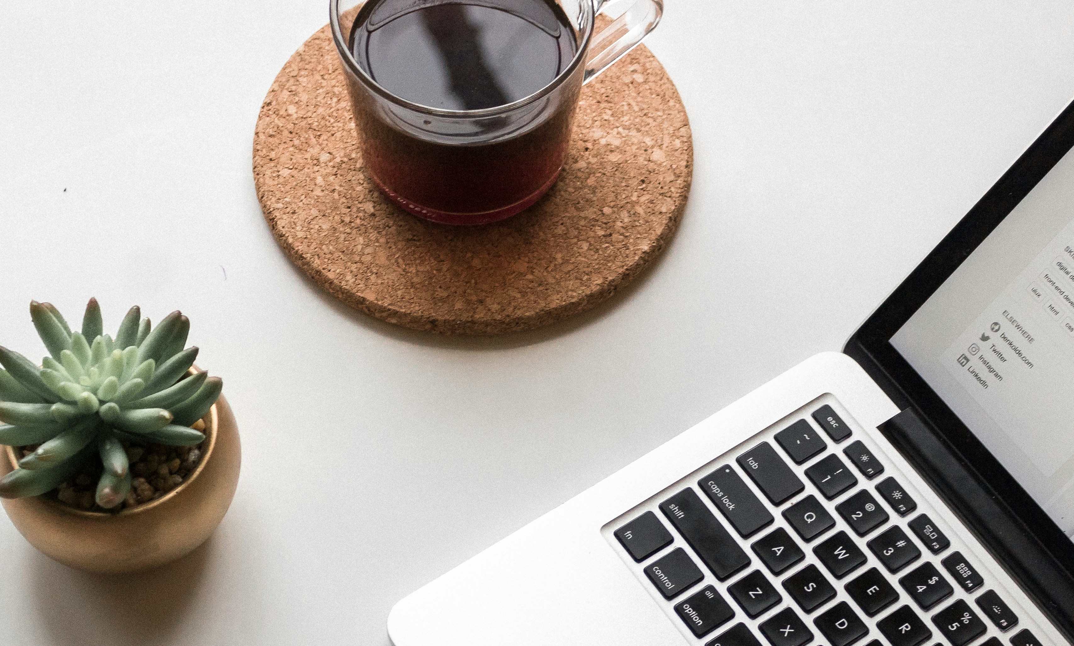 space gray iPhone X beside turned on laptop beside coffee and succulent plant