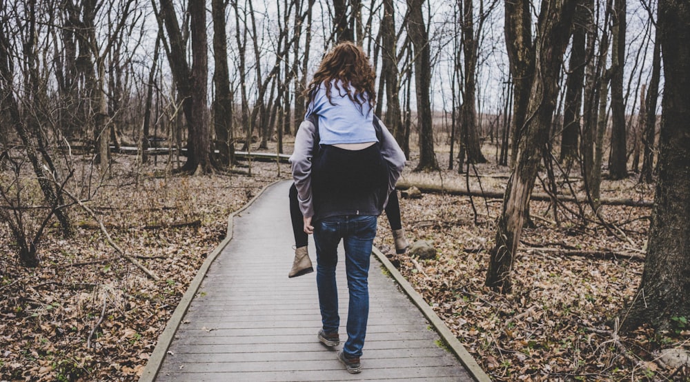 man carrying a woman on his back in forest path