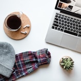 A cozy workspace featuring a laptop and wireless earbuds.