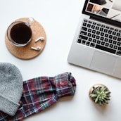 A tidy office workspace featuring a laptop, glasses, and a cup of coffee.