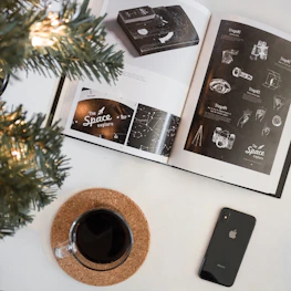 A curious person reading on a digital device surrounded by icons of planets, animals, and inventions.