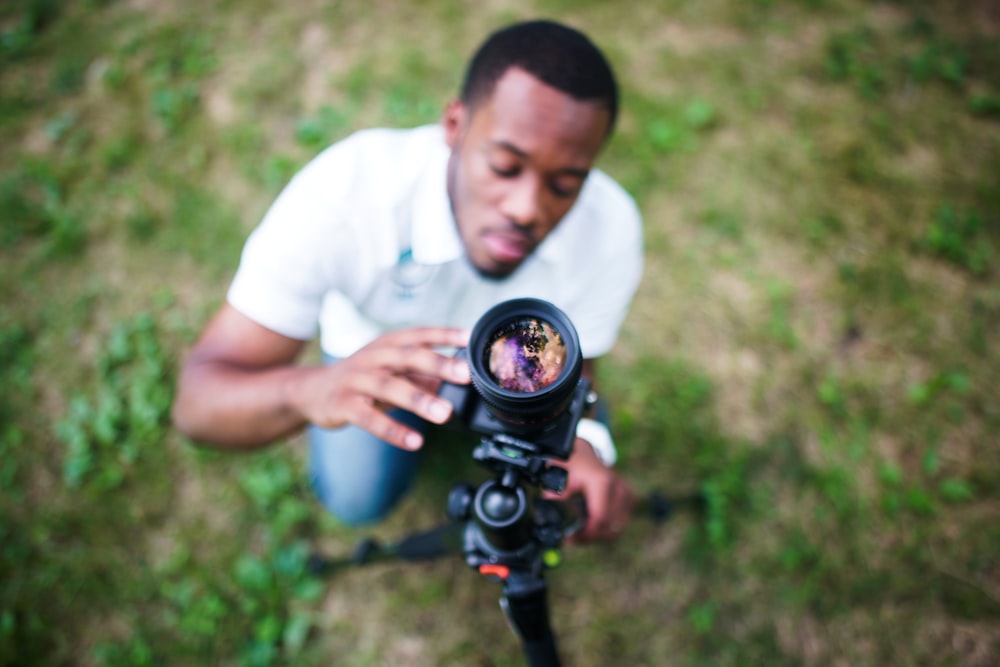 man sitting while holding black DSLR camera