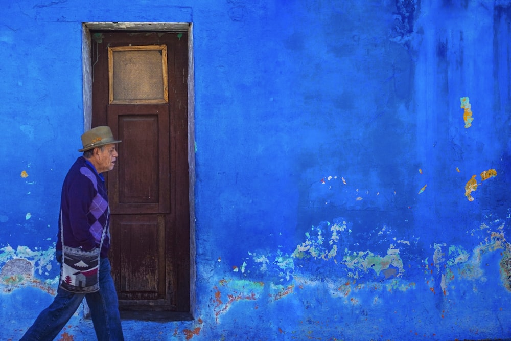 hombre caminando al lado de un edificio pintado de azul
