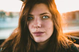 A close-up portrait of a smiling woman bathed in soft natural light.