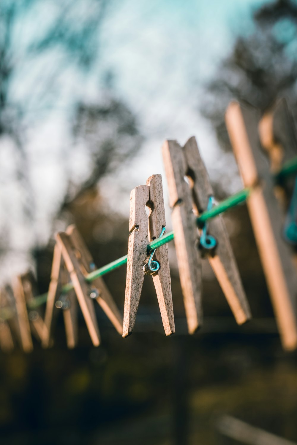 selective focus photography of brown clothes clips hanged on green cable outdoor at daytime