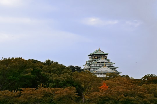 white pagoda surrounded trees in Osaka Castle Park Japan