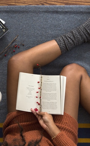 opened book on person's lap with gray socks