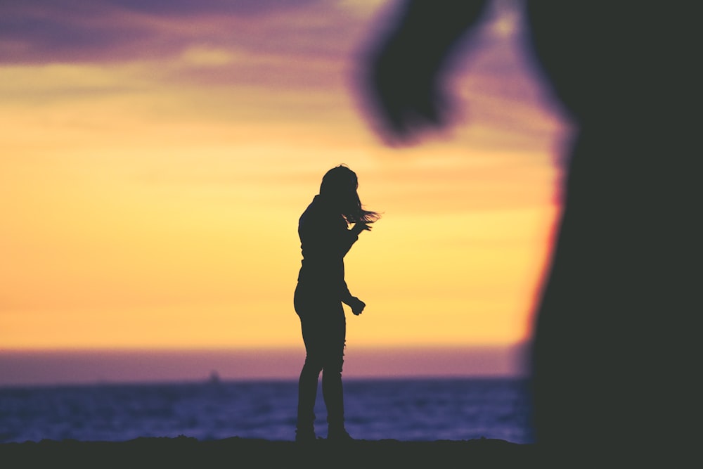 silhouette photography of woman standing at beach