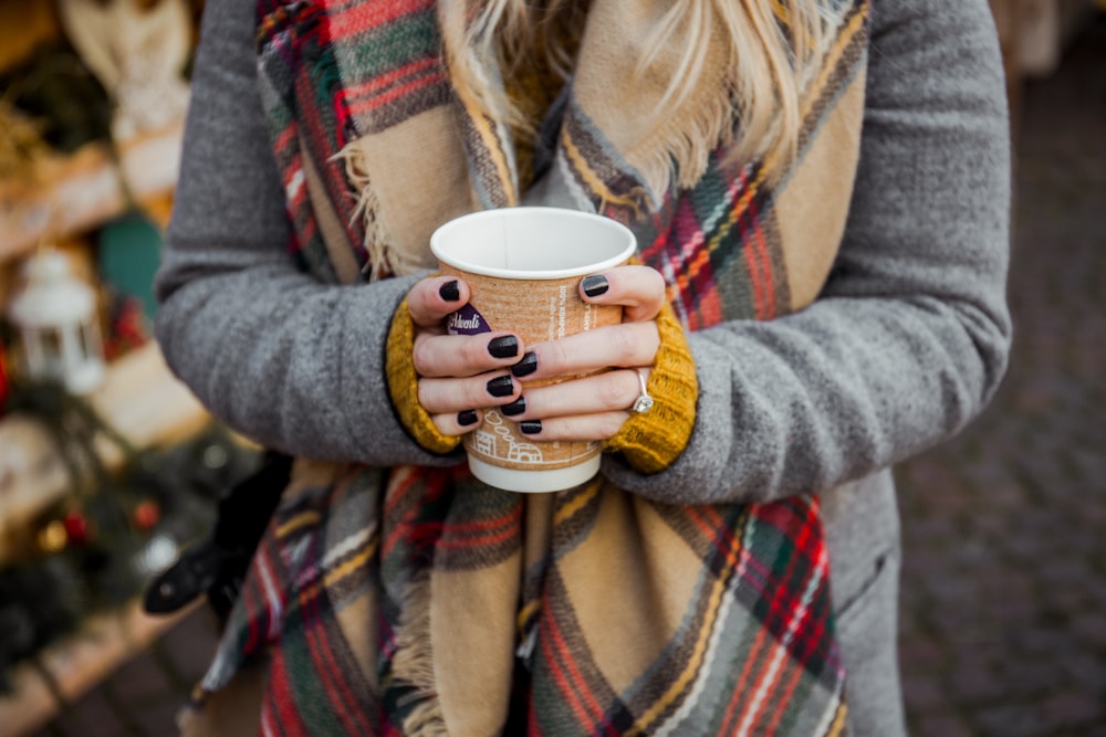 closeup photo of woman holding brown plastic cup in room