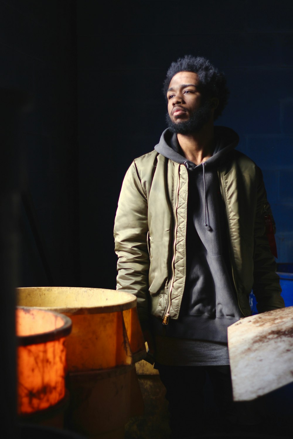 man in green and black jacket standing near containers