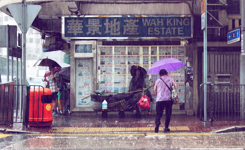 Frau, die auf dem Bürgersteig geht, während sie einen Regenschirm hält