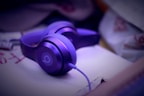 A close-up of stylish modern headphones with a purple background.
