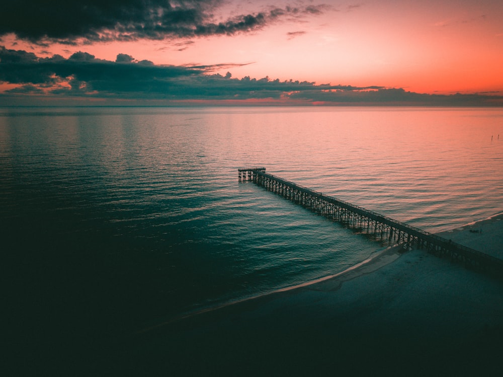 black metal dock on calm water under golden hour