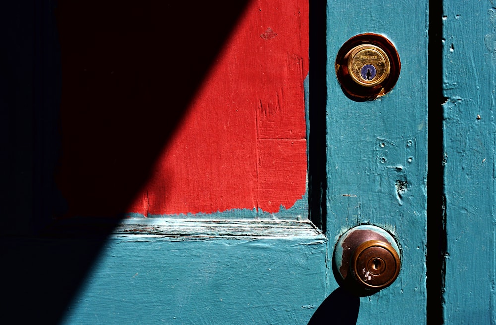 closed teal wooden door with brass-colored door knob