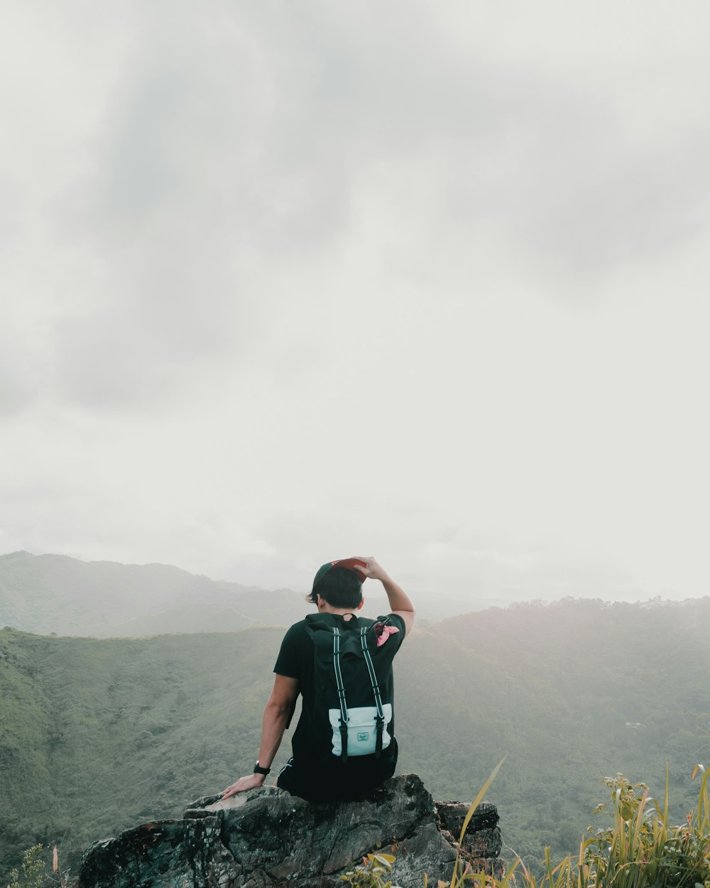 man sitting on rock and facing on mountain