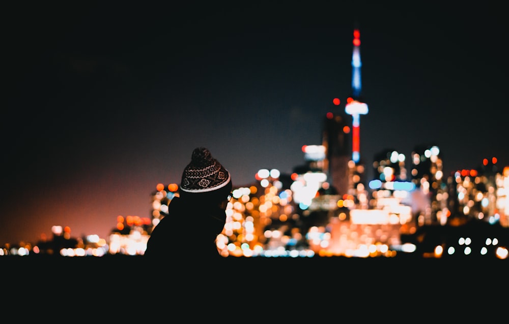 person wears hat beside building on bokeh photography