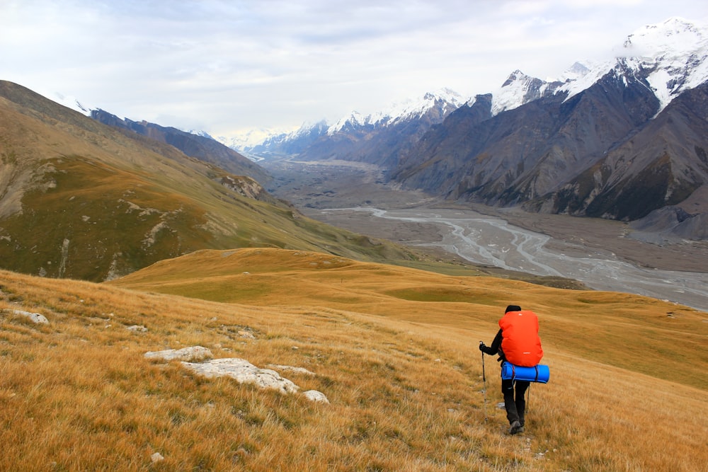 man with hiking bag climbing on mountains