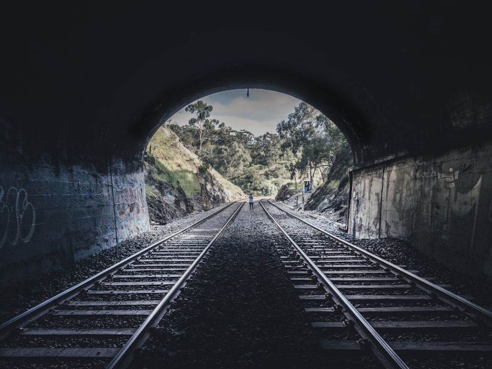 person standing between train rails at daytime