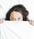 woman covering her face with blanket