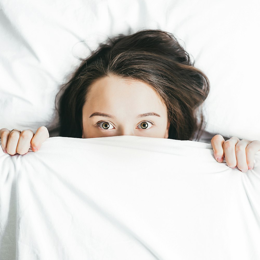 A woman hides under her duvet