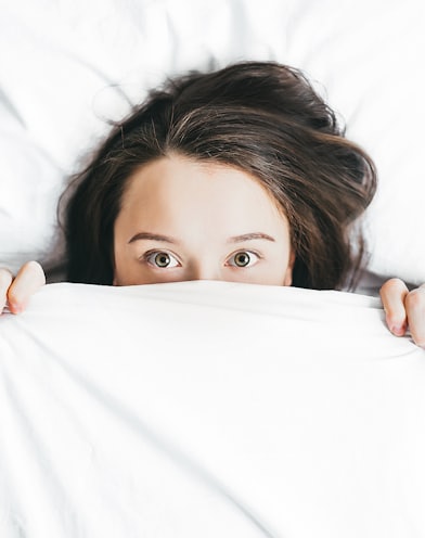 woman covering her face with blanket