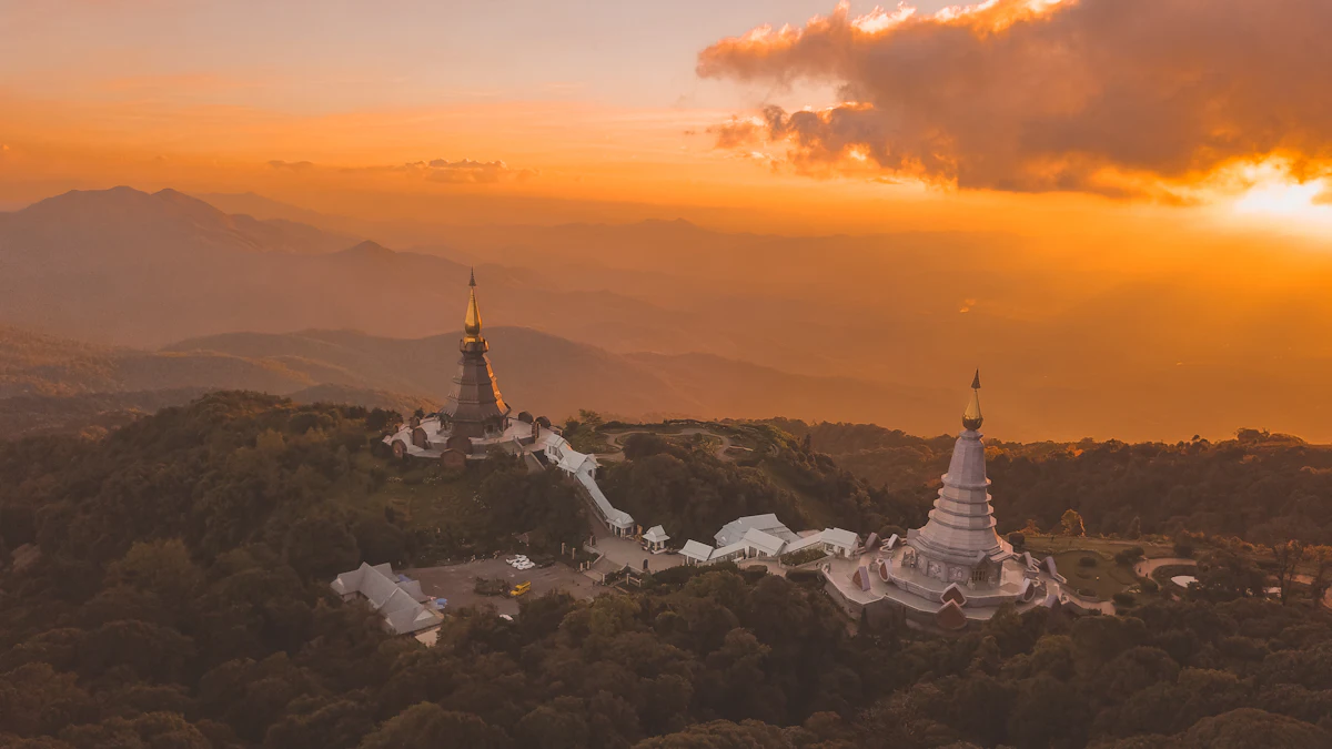 Two pagodas on a forested ridge of Doi Inthanon in golden light, with hazy ranges behind