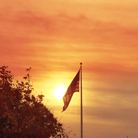 A yellow ribbon fluttering in the breeze against a warm charcoal sky at dusk.