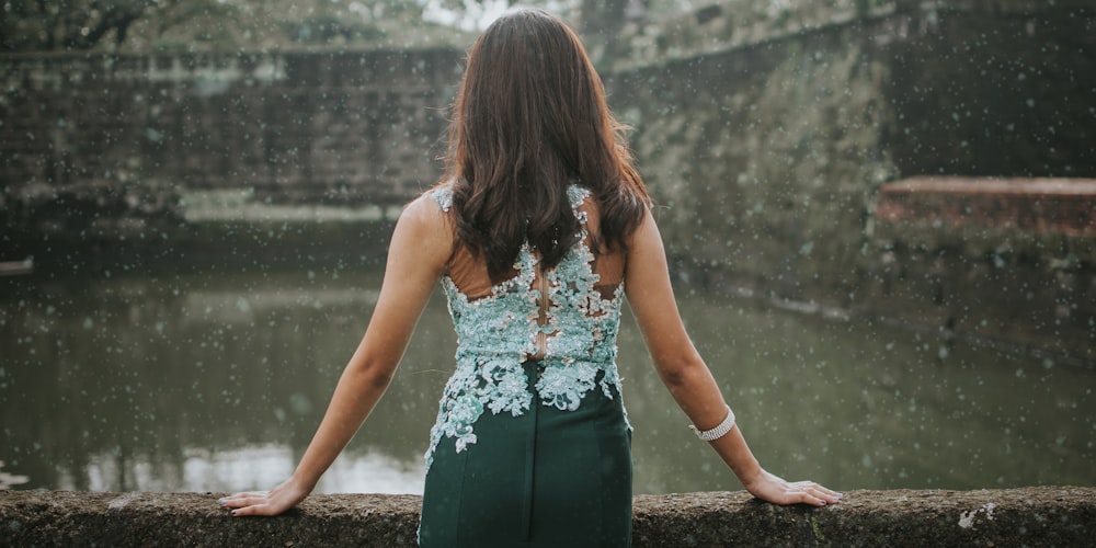 woman standing near wall facing body of water