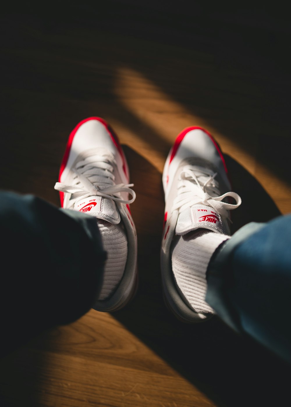 persona sosteniendo zapatillas Nike blancas y rojas
