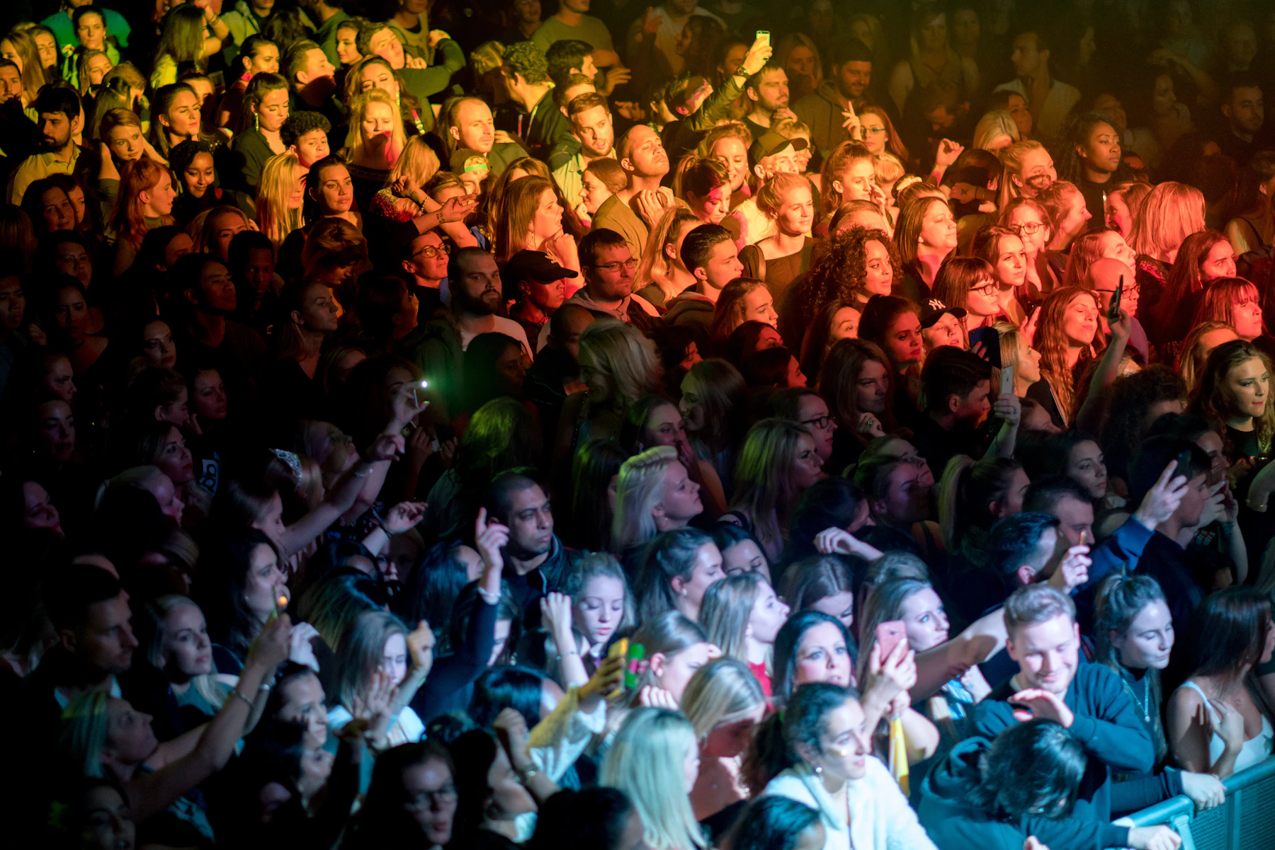 Crowd gathered around a live music stage under vivid lights