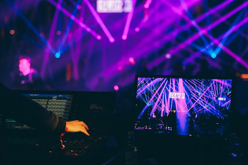 person holding black laptop computer inside club with purple lights