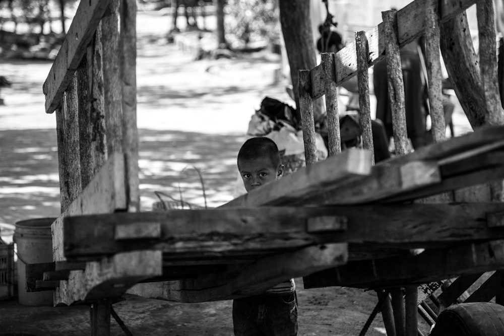 grayscale photography of child standing behind trailer