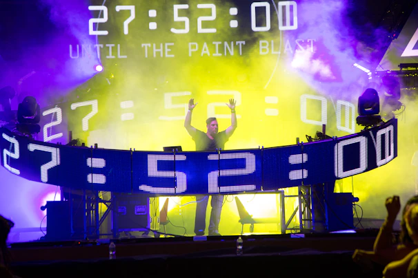 DJ booth surrounded by foam with excited crowd hands raised in the air, showing a lively party vibe.