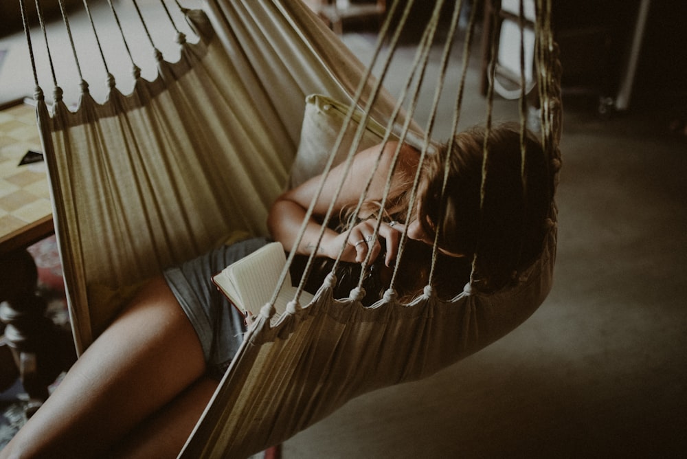 woman reading book on beige hammock